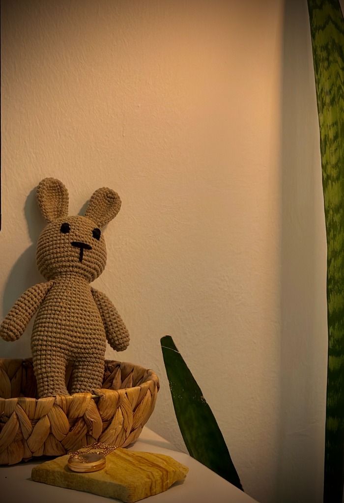 Handcrafted soft plush bunny in basket with green leaves